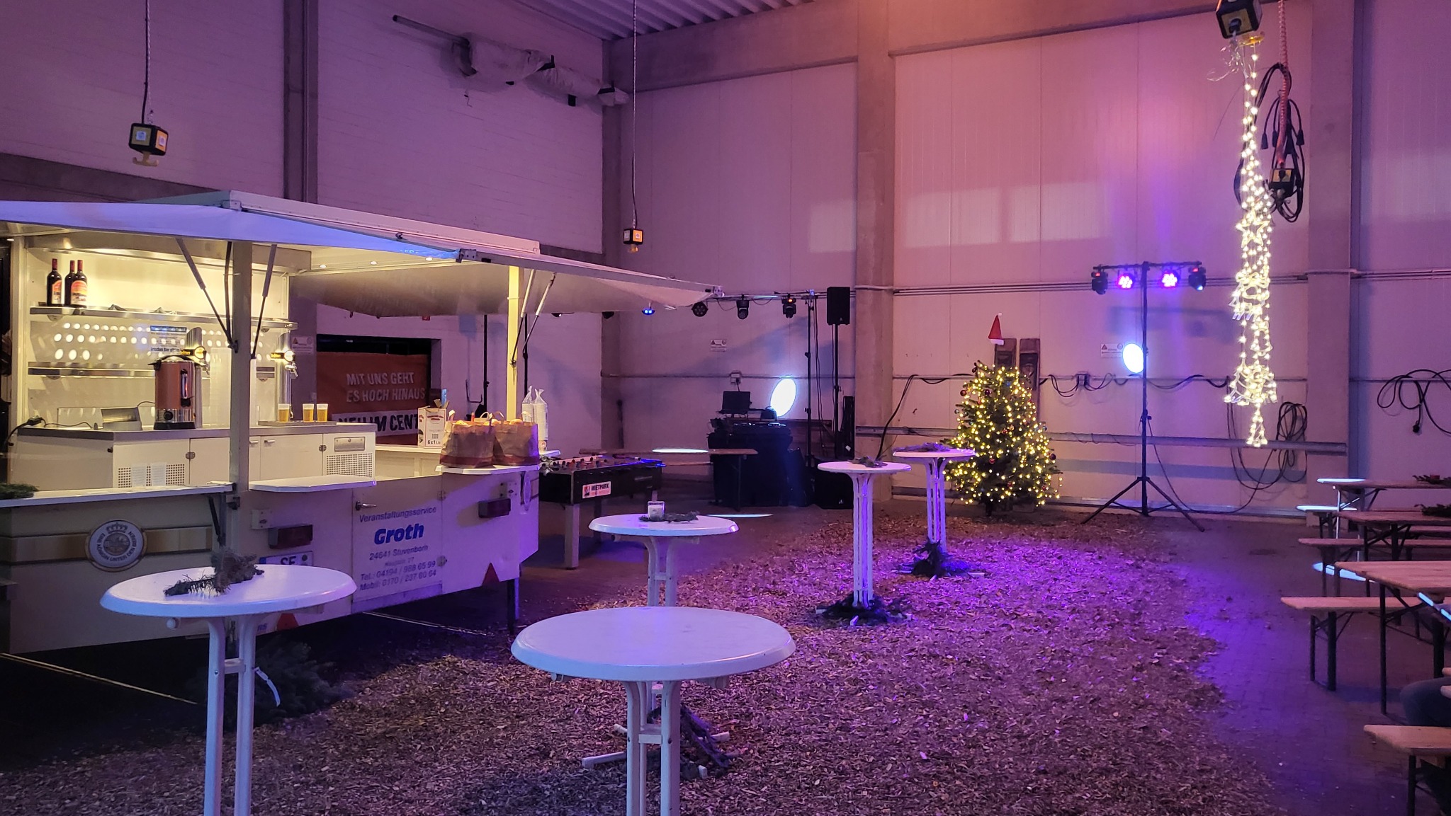 Eventhalle mit farbiger Beleuchtung und aufgebauter DJ-Technik